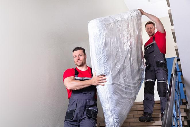 two people carrying a box spring out of a bedroom in Altamont, IL